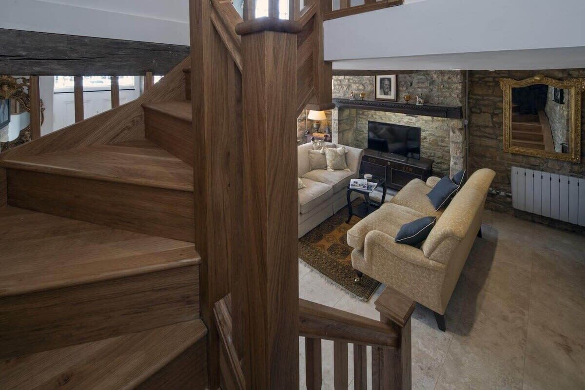 A wooden staircase leading to a living area with a fireplace, sofa, and television.