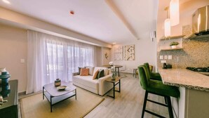 A modern living room with a sofa, coffee table, and a dining area with a table and chairs.