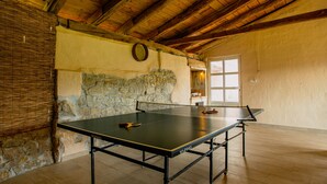 Una mesa de ping pong en una habitación con paredes de piedra y vigas de madera.