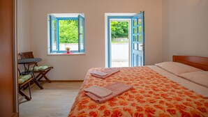 Un dormitorio con una cama, dos ventanas, una silla y una mesita.
