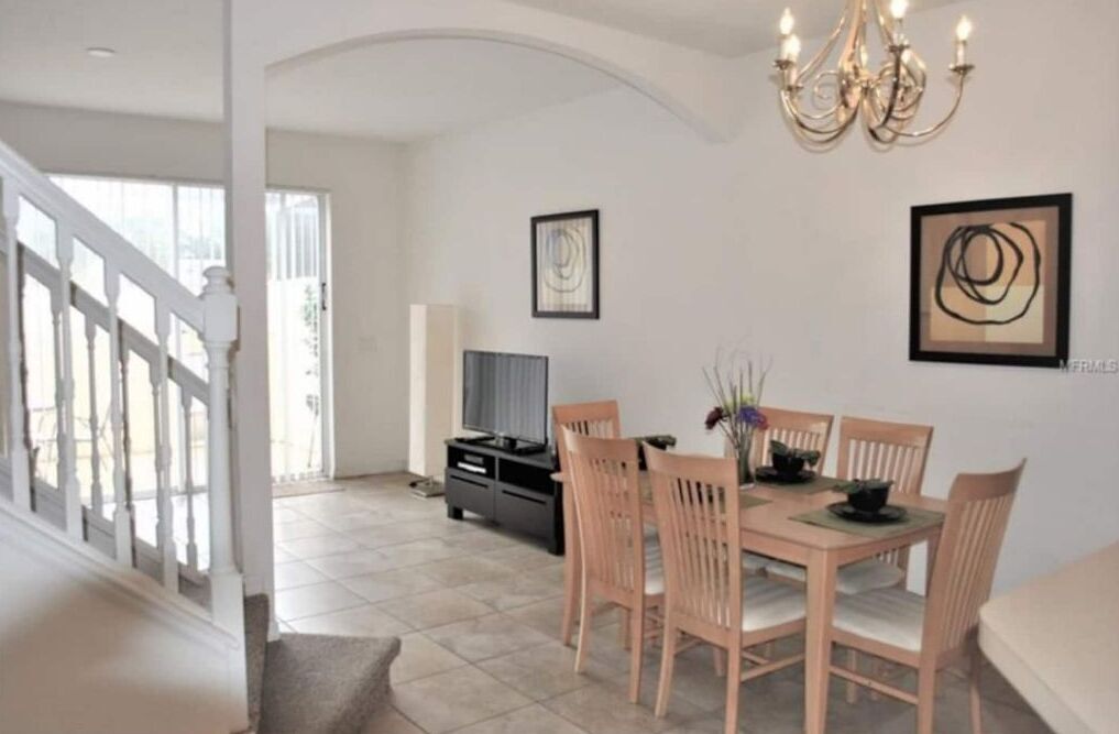 A dining area with a wooden table and chairs, a chandelier, and artwork on the walls.