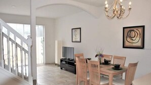 Uma sala de jantar com uma mesa e cadeiras de madeira, um candelabro e obras de arte nas paredes.