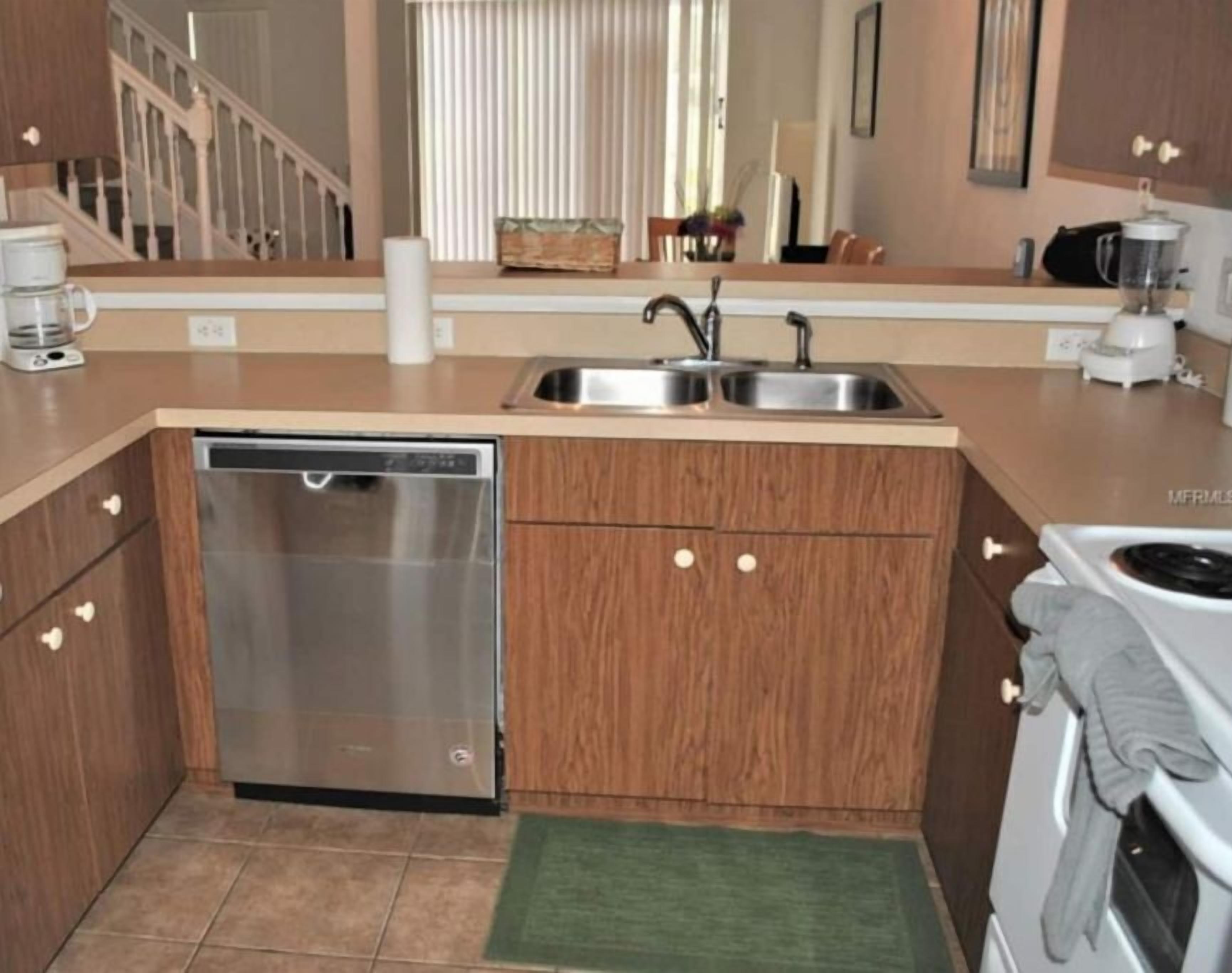 A compact kitchen with a dishwasher, double sink, and a stove.