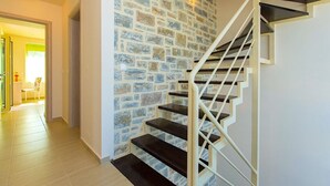 A staircase with a stone wall backdrop, a wooden floor, and a white railing. - Blue Mare Villa, privacy and relaxation! (Rethymnon)