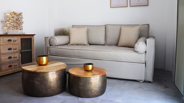 Una sala moderna con un sofá, dos mesitas redondas y un mueble de madera.