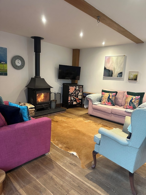Cozy living room with a black stove, flat-screen TV, and comfortable seating area.