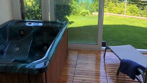 Aurinkoinen huone, jossa on poreallas ja suuri liukuovi, joka johtaa ulos nurmikkoalueelle ja järvelle.