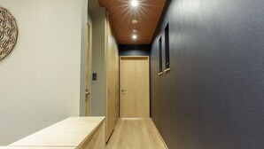 Ein schmaler Flur mit einer hölzernen Bank, einer Tür am Ende und einer Wand mit einem geometrischen Muster.