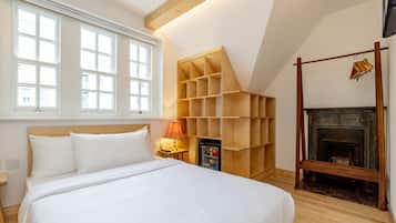 A bedroom with a large bed, a wooden shelving unit, a fireplace, and a window with multiple panes.
