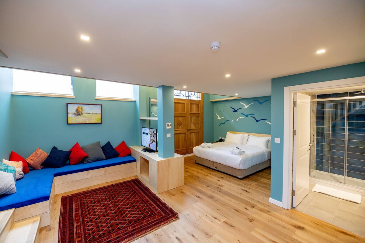 Une chambre moderne équipée d’un lit, d’un canapé, d’un bureau et d’un espace douche.