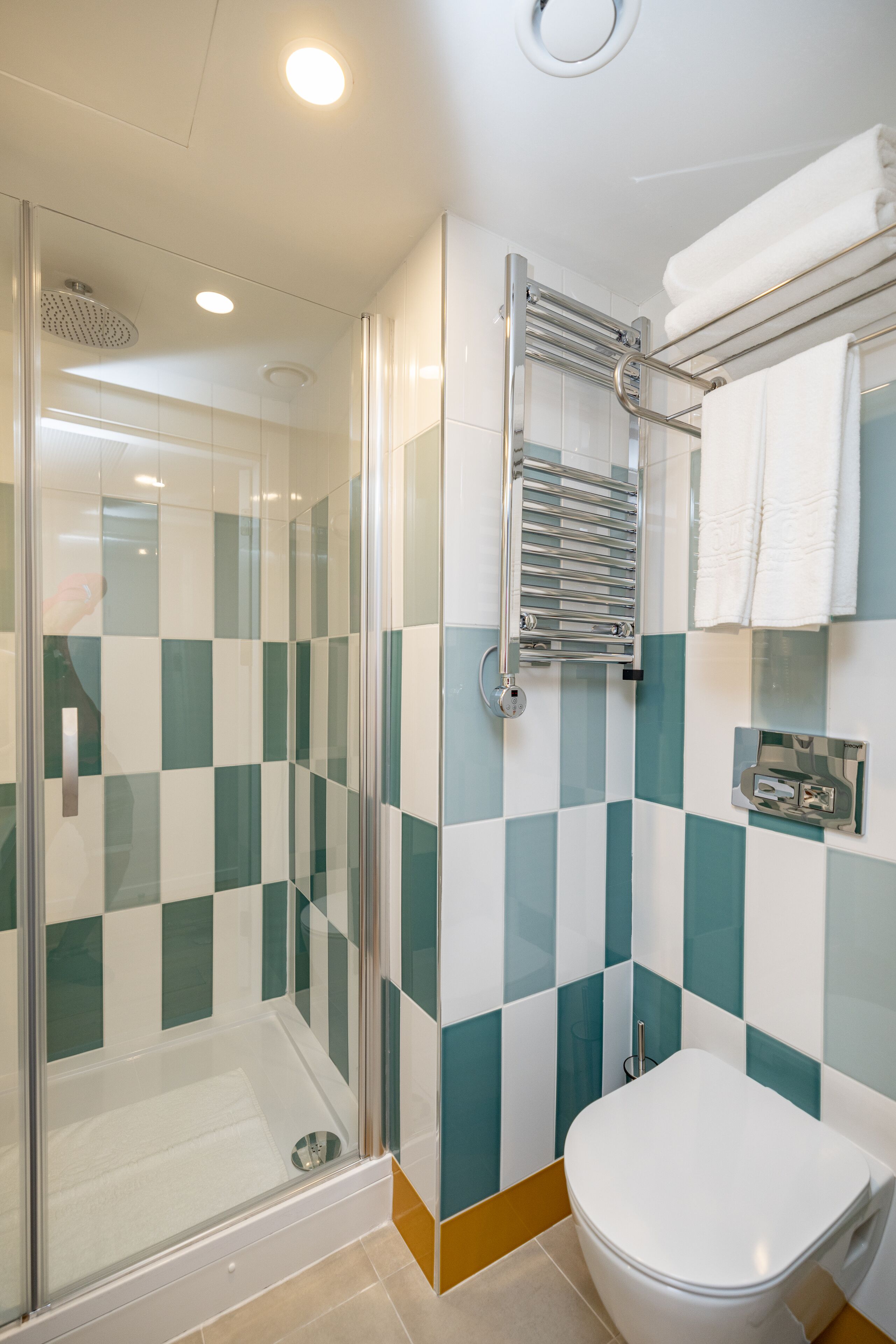 Un bagno moderno con cabina doccia in vetro, un water bianco e un porta asciugamani.