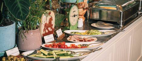 Un bufé con diversos alimentos, como aceitunas, tomates, pepinos y carnes.