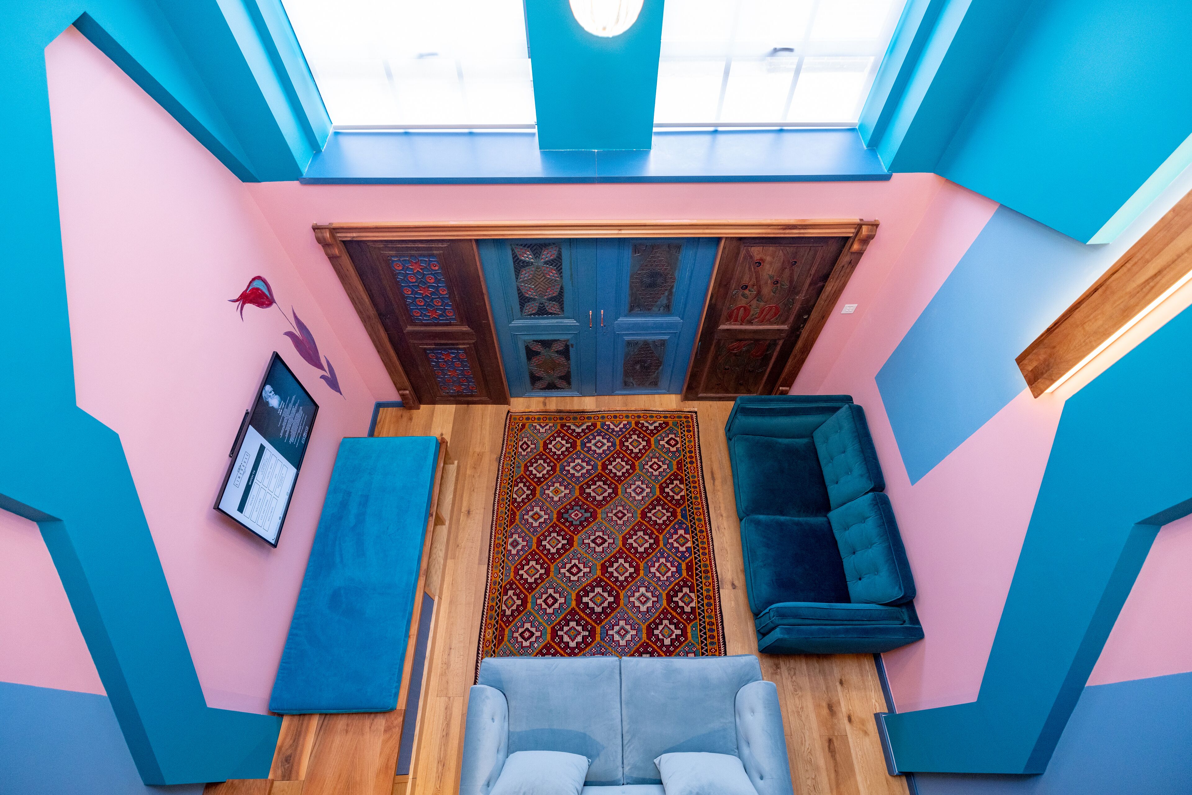 A room with a skylight, a patterned rug, a blue sofa, and a wooden door with decorative panels.