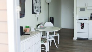 A dining area with a white table and chairs, a potted plant, and a wall-mounted picture. - 1610 🌸 free parking 🚙🅿️, fast WIFI💻 (Honolulu)