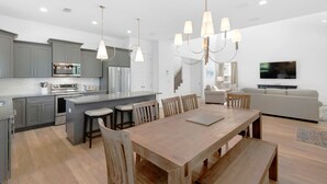 A modern kitchen with grey cabinets, stainless steel appliances, and a central island with bar stools.