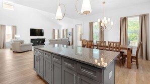 A spacious kitchen with granite countertops, a dining area with wooden chairs, and a large island.