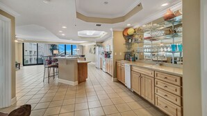 A spacious kitchen with a central island, wooden cabinets, and a glass display case. - Lighthouse on the Bay unit 213- 3bed/3bath -Large Pet Friendly Condo- Bay Views! (Orange Beach)