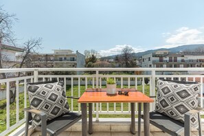 A balcony with a table and two chairs, a potted plant, and a pair of sunglasses on the table.