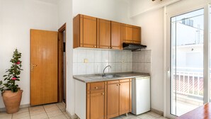 Une cuisine compacte avec des meubles en bois, un lave-vaisselle encastré et une grande fenêtre donnant sur l’extérieur.