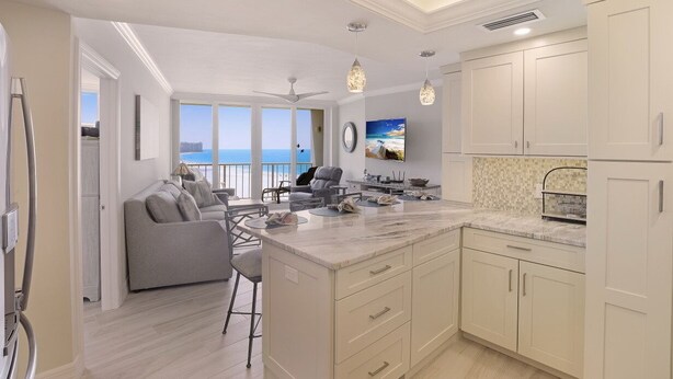 Una cocina moderna con una isla grande, armarios blancos e iluminación colgante.