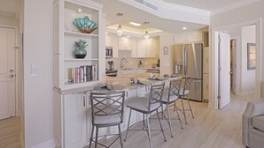 Una cocina moderna con una isla central, taburetes de bar y estanterías empotradas.