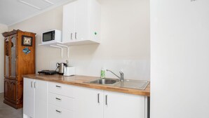 Una cocina moderna con armarios blancos, encimera de madera, microondas, hervidor, tostadora y un lavabo.