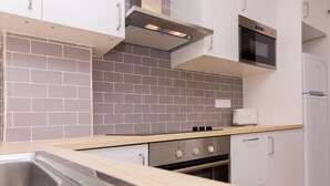 A modern kitchen with grey tiled backsplash, stainless steel appliances, and light wooden countertops. - Isla Saint Tropez Apartment Javea Arenal, with Pool, Wifi, AC and recently Refurbished (Javea / Xàbia)