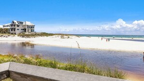 Una propiedad frente al mar con una casa grande, una playa de arena y una masa de agua tranquila.