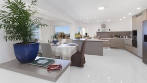 Een moderne keuken met witte kasten, een centraal eiland en een eethoek met een tafel gedekt voor twee personen.
