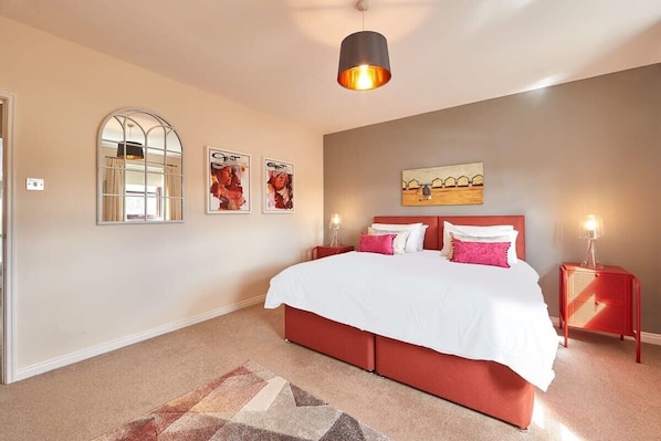 Une chambre à coucher avec un grand lit, un miroir et des œuvres d’art accrochées au mur.