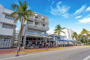 Um edifício com vários andares, design moderno, com varandas e um restaurante no térreo.