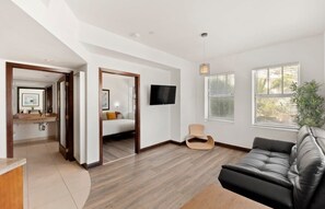 A modern living room with a sofa, a TV, and a plant.