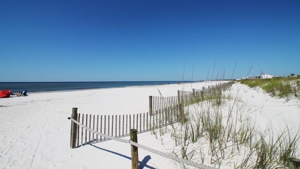A beach with a wooden fence and a building in the background. - SHORE BEATS WORK IS 500 STEPS TO BEACH! MODERN, IMMACULATE TOWNHOME! (Mexico Beach)