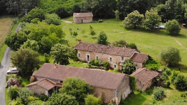 Vista aérea de una propiedad rural con varias construcciones rodeadas de abundante vegetación.