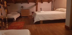 Una habitación con dos camas, un aparador de madera, un radiador y una alfombra roja estampada.