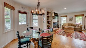 A spacious living room with a large round glass table, a comfortable sofa, and a fireplace.