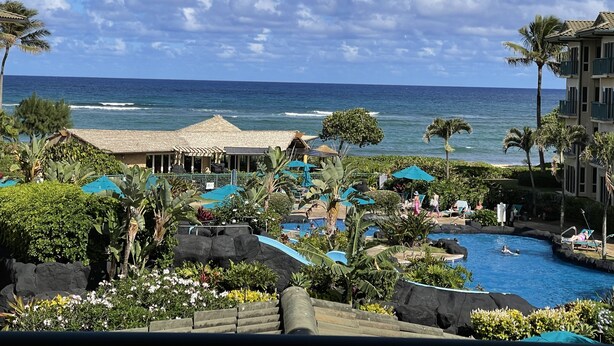 A resort with a pool, palm trees, and a view of the ocean.