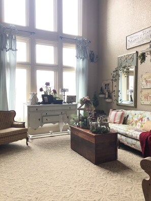 Relax in this inviting living room with a large window, ornate dresser, and plush sofa.