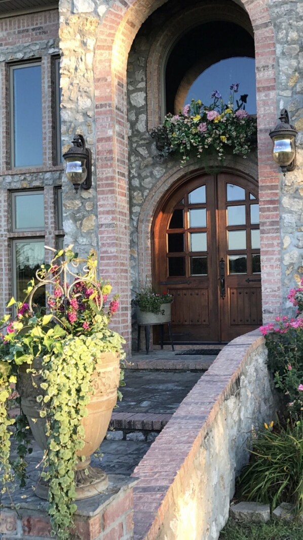 Traditional stone building with an arched entrance, flanked by lanterns and a planter with flowers.