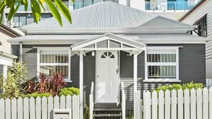 Een laag huis met een witte picket fence, een voordeur en een klein voortuintje.