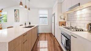 Een moderne keuken met een centraal eiland, houten kastjes, een gasfornuis en hanglampen.