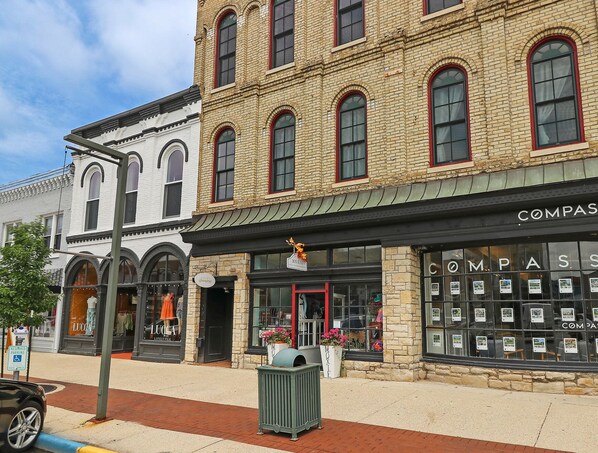 A row of brick buildings with storefronts, including a Compass real estate office. - Downtown Lake Geneva Glamping Loft Walk to Lake Bar Kitchen Swings Sleeps 12 (Lake Geneva)