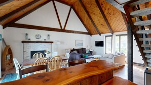 Amplia sala de estar con techo de madera, chimenea, un conjunto de sofás y una mesa de comedor con sillas.