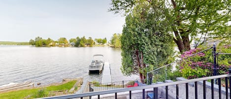 A boat docked at a pier with a view of a lake and trees in the background.