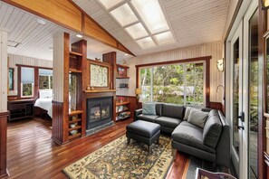 A cozy living room with a fireplace, a large sectional sofa, and a wooden floor.