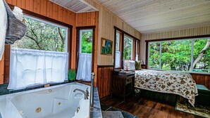 Un baño con una bañera grande, paredes de madera y una ventana con vistas a la vegetación.