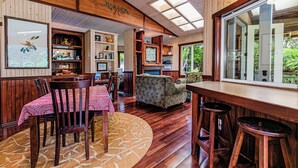 Un interior acogedor con comedor, chimenea y un ventanal con vistas a la vegetación.
