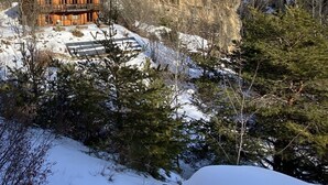 Une cabane en bois dotée d’un balcon, entourée d’un paysage enneigé et d’arbres.