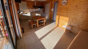 L’intérieur d’un chalet chaleureux, avec une table à manger en bois, un banc et un canapé.