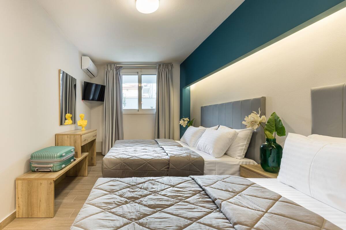 A modern hotel room with two beds, a TV, a desk, and a window with curtains.